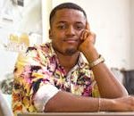 Young man wearing a colorful floral shirt, posing with a thoughtful expression indoors.