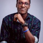 Charming young man in eyeglasses posing confidently with a smile against a purple background.